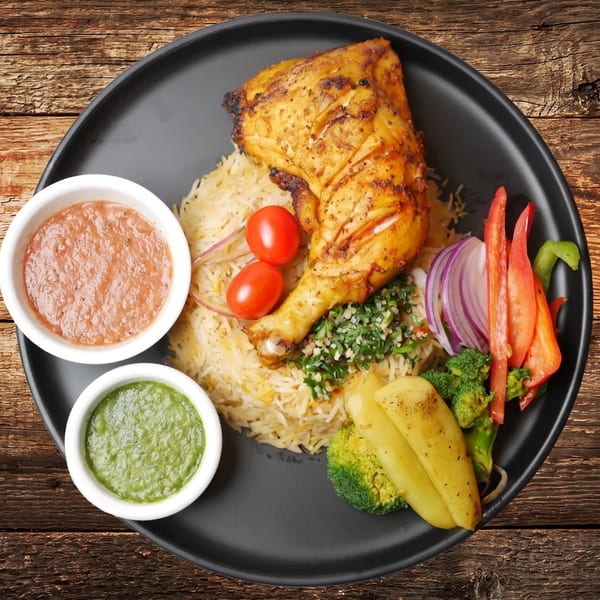 Grilled chicken leg with rice, vegetables, and two dipping sauces on a black plate.